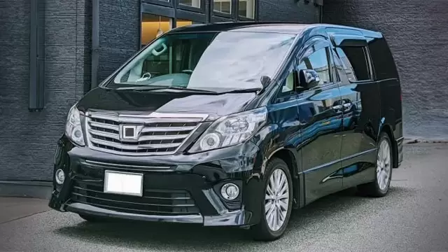 黒い高級車(葬儀用)の写真。建物の前に停車している。